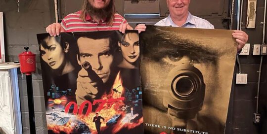 Nikolai Adams (left) with a Goldeneye theatrical poster, and Sean Adams with a Goldeneye advance poster.